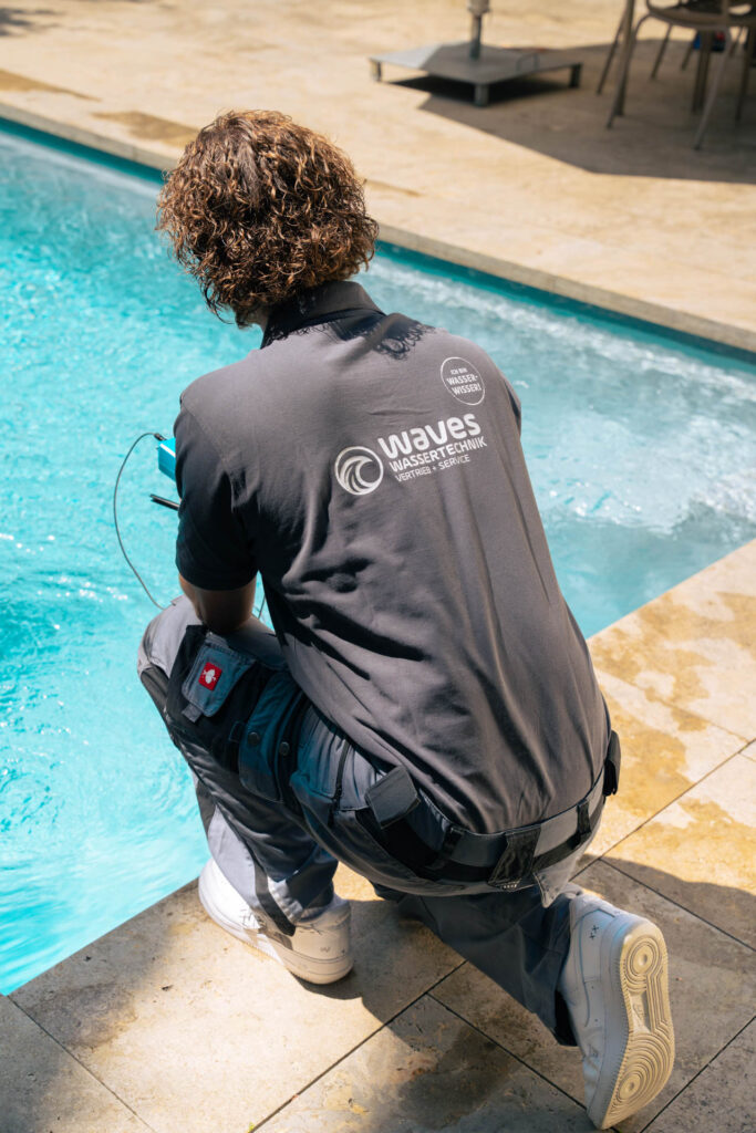 Servicetechniker von Waves Wassertechnik prüft die Wasserqualität eines Pools mit einem Messgerät.