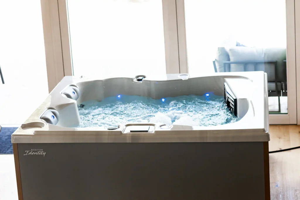 Whirlpool im Innenraum mit sprudelndem Wasser und blauer LED-Beleuchtung vor großen Fenstern.