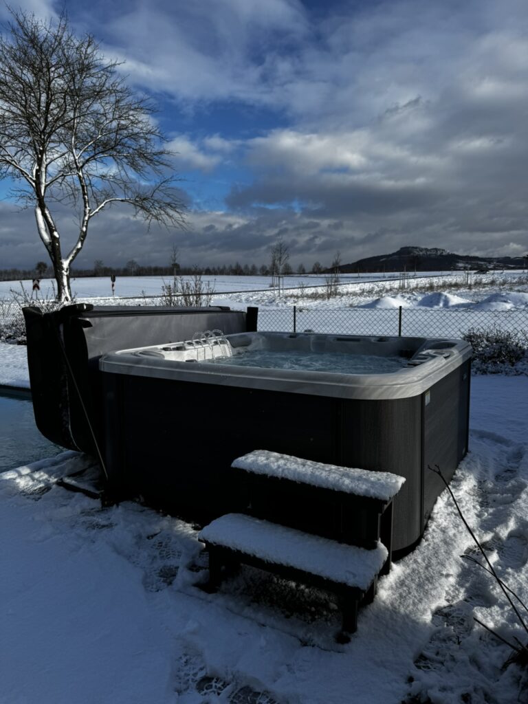 Whirlpool auf Holzpodest im Schnee.
