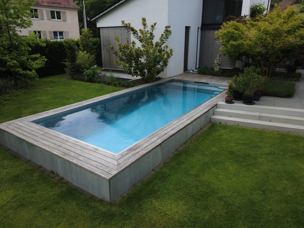 Geradliniges Skimmerbecken aus Edelstahl mit modernem Design, umgeben von einem harmonisch gestalteten Garten.