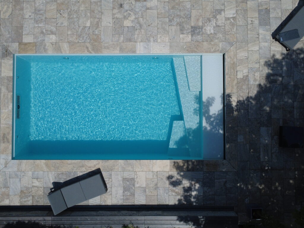 Vogelperspektive mit Oblique-Treppe auf Gartenpool. Der Pool ist durch eine Steinterrasse eingebettet.