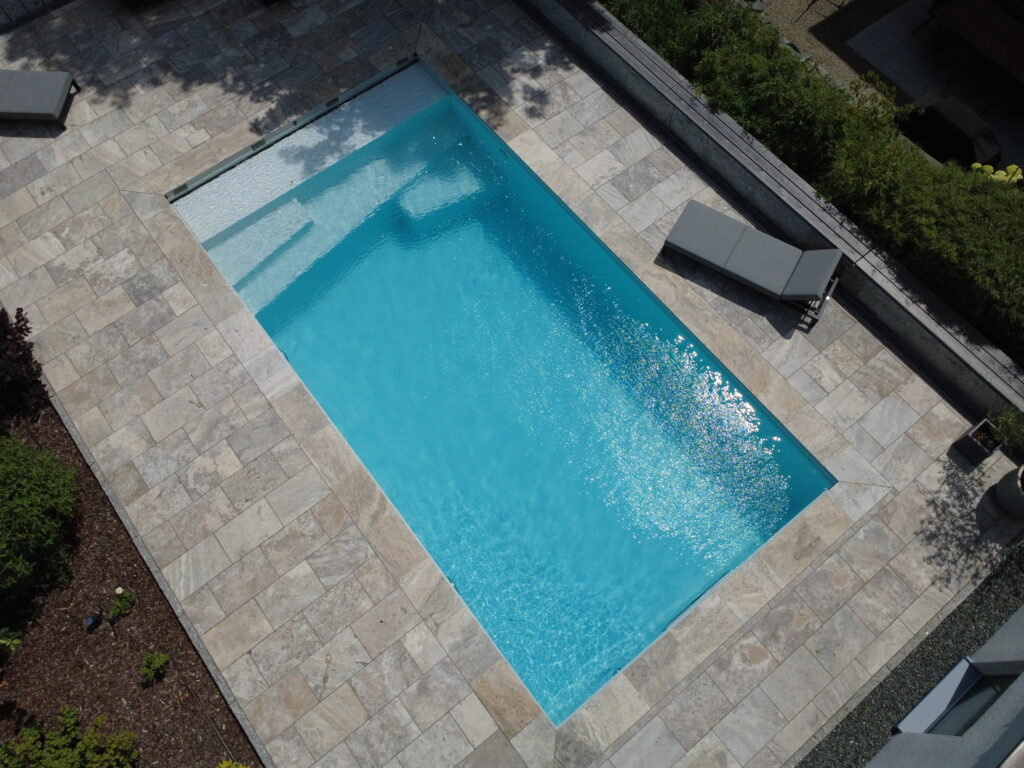 Vogelperspektive auf Gartenpool mit Oblique-Treppe und Gartenliege an der rechten Seite. 